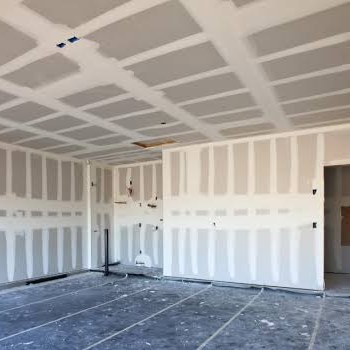 First coat — Joint compound bedded over every seam and fastener row, floors protected.